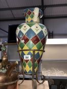 A colourful glazed amphora vase on a metal tripod stand