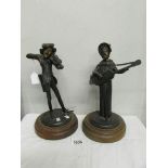A pair of signed metal figural candlesticks as musicians.