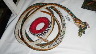 A beaded snake with lizard in mouth.