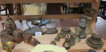 A shelf of brass weights, iron weights and flat irons.