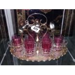 A tea stand with metal mounted glass tea cups and 6 small cranberry glass tumblers.
