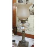 A brass oil lamp with glass font and shade.