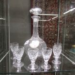 A glass decanter with ceramic label and 6 glasses.