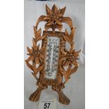 An early 20th century thermometer in a carved fruit wood frame, in good condition.