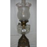 An oil lamp with metal base, glass font and complete with shade.