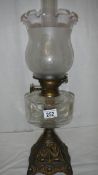 An oil lamp with metal base, glass font and complete with shade.