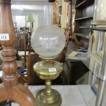 A brass oil lamp with etched glass shade.
