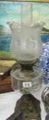 An oil lamp on metal base with glass font and etched glass shade.