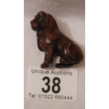 A carved rosewood netsuke as a dachsund, with small ivory disc inset, 2" tall, in good condition.
