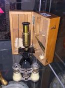 A cased student microscope and a pair of opera glasses.