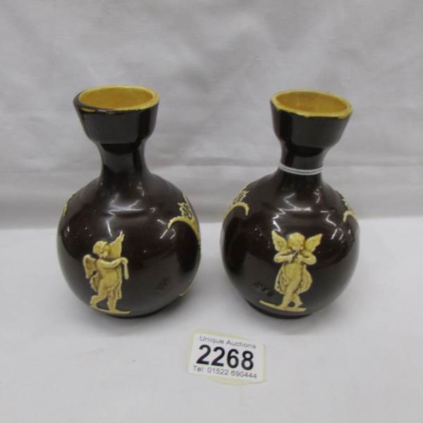 A small pair of pottery vases decorated with cherubs.