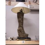 A table lamp in the shape of a ladies knee high boot with leopard print