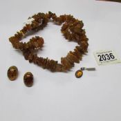 A rough amber necklace together with a pair of clip on amber earrings and an amber pendant.