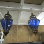 A pair of metal lanterns with blue glass panels.
