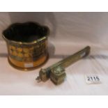 A heavy brass trench art bottle holder decorated with flowers and an ornate brass inkwell/pen case.