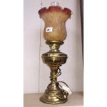 A brass oil lamp with amber glass shade
