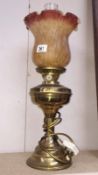 A brass oil lamp with amber glass shade