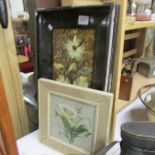 A framed floral decorated tile and a lily picture.