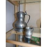 A large pewter lidded tankard and a pewter measure.