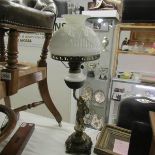 A cast iron figural oil lamp with white glass font and shade.