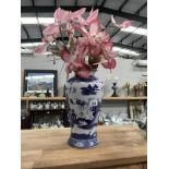 A blue & white Willow pattern vase with artificial flowers