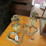 A pair of brass 'cobra' candlesticks.