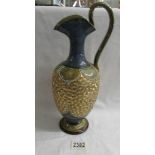 An early Doulton pitcher with long handle and featuring gold coloured floral pattern.