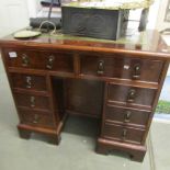 A small mahogany kneehole desk with leather inset top.