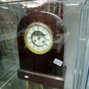 A mahogany domed top mantle clock with open escapement.