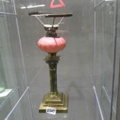 A Victorian brass Corinthian column oil lamp base with pink glass font,