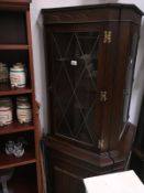 A darkwood stained corner cupboard with leaded glass door