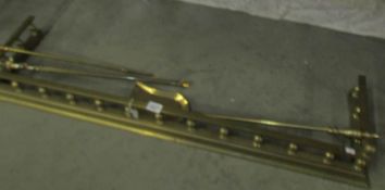 A brass fender and a set of 3 brass fire irons.