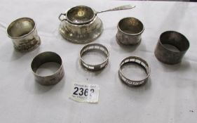 6 assorted silver napkin rings and a silver tea strainer.