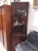 A darkwood stained corner cupboard with astragal glazed door
