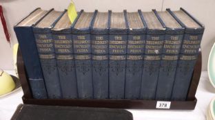 A set of 10 Children's encyclopaedia and a bakelite book rack.