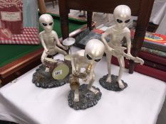 3 figures of aliens playing musical instruments