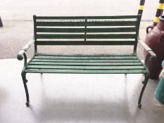 A green painted wooden bench with metal frame