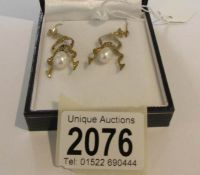 A pair of pearl drop earrings set diamonds.