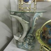 A glass topped table with dolphin base,.