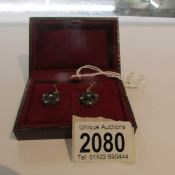 A pair of drop earrings set with amethysts and diamonds in a red box.