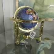 A small gem set table globe on brass base.