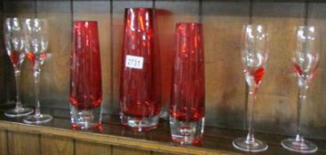 3 red glass vases and 4 champagne flutes.