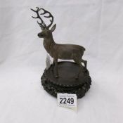 A cast metal figure of a stag on wooden base.