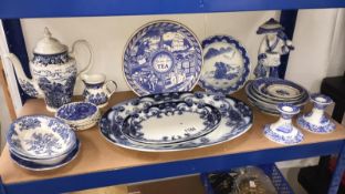A shelf of blue and white pottery including Burslem Iris meat plates, Spode candlesticks etc.