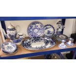 A shelf of blue and white pottery including Burslem Iris meat plates, Spode candlesticks etc.