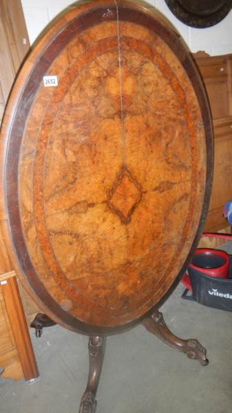 A Victorian walnut oval inlaid tip top table with bird cage base.