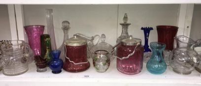 A shelf of glass biscuit barrels, jugs, vases including cranberry etc.