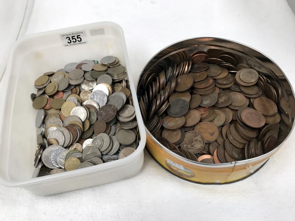 A tin of British coins and a tub of foreign coins