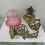 A Victorian brass wall mounting oil lamp with brass font and cranberry acid etched lamp shade.