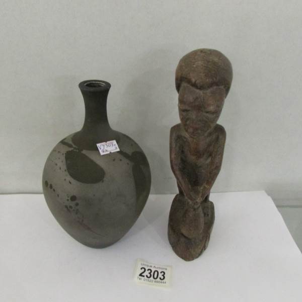 A wooden native figure and a pottery vase with depictions of leaves, marked SR.